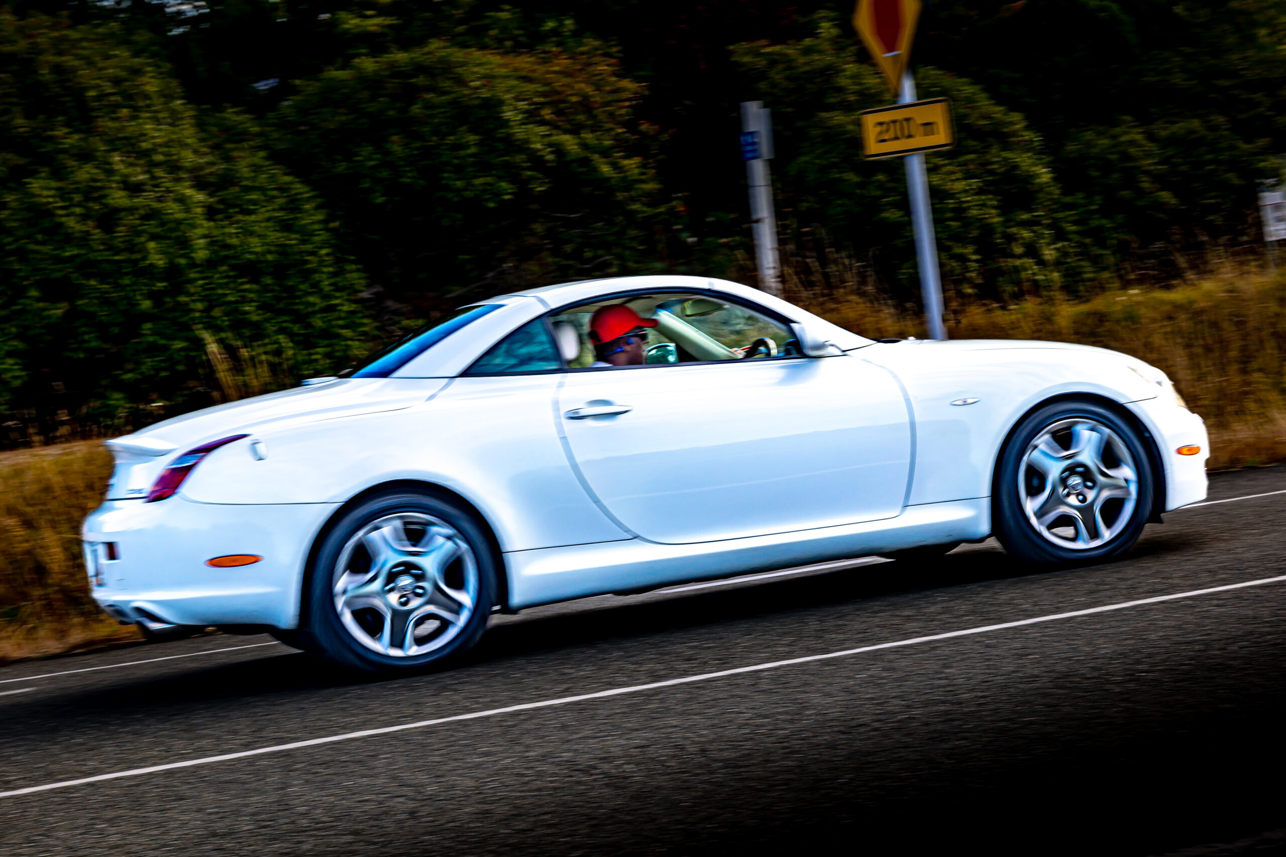 RentAClassics Lexus SC430 side on on road with driver in red cap